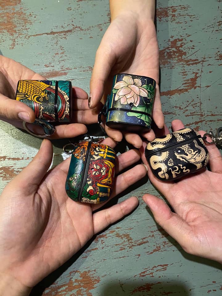 Hand-painted leather AirPods cases held by Vietnamese artisans – SaigonCraft’s signature handcrafted accessory